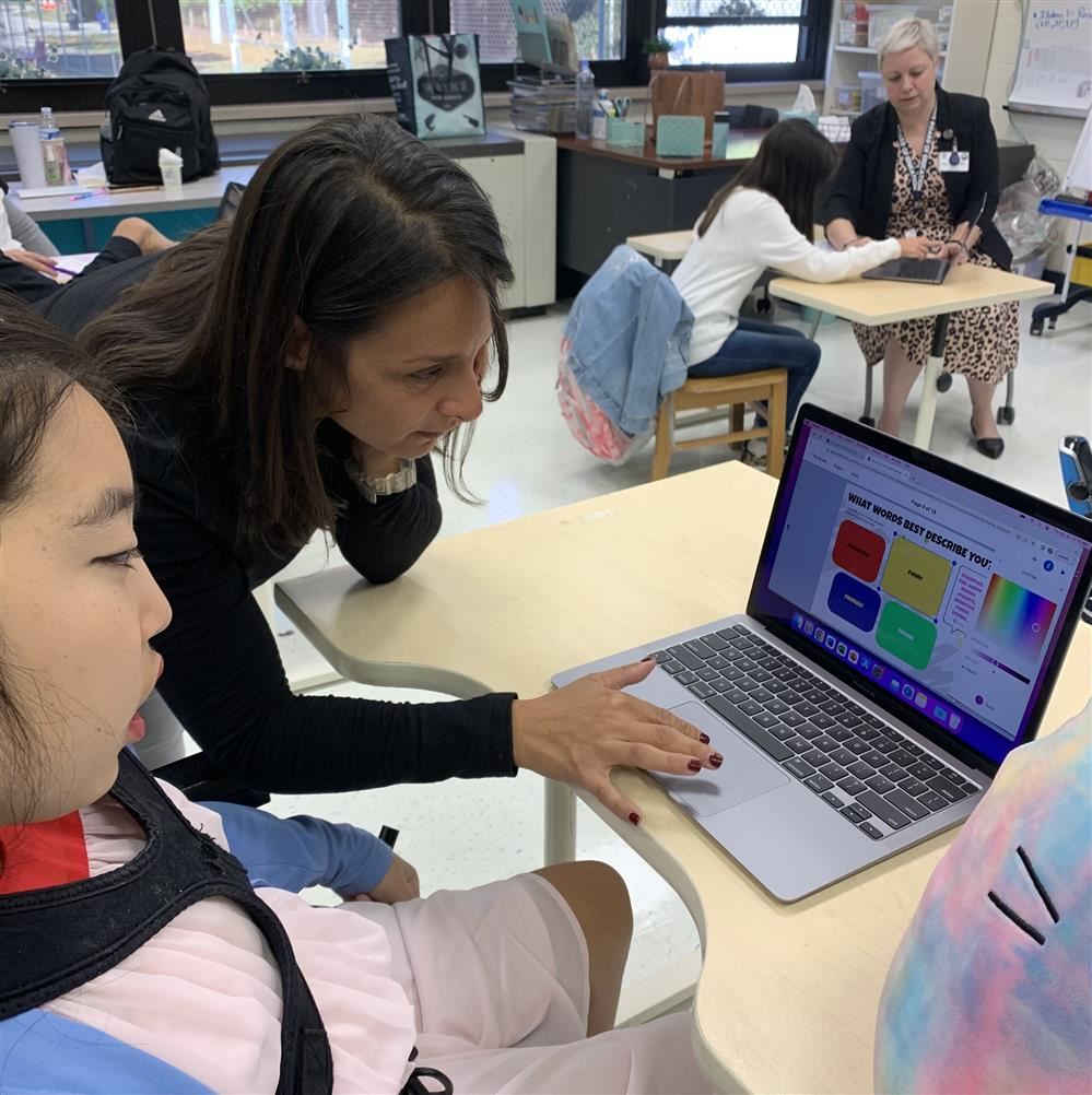  student working with her teacher on the computer.